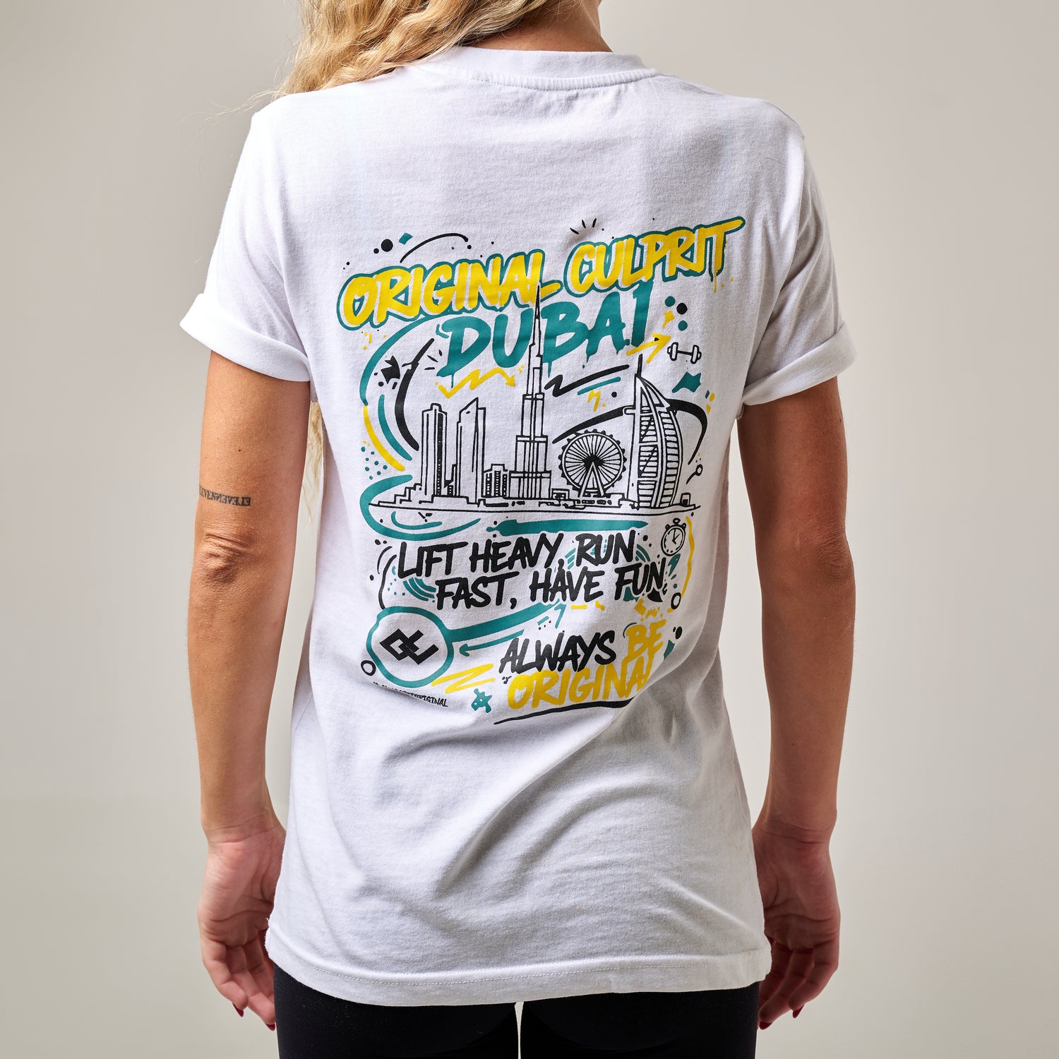 Woman wearing a white t-shirt with colourful graphics and text on the back, against a plain background.